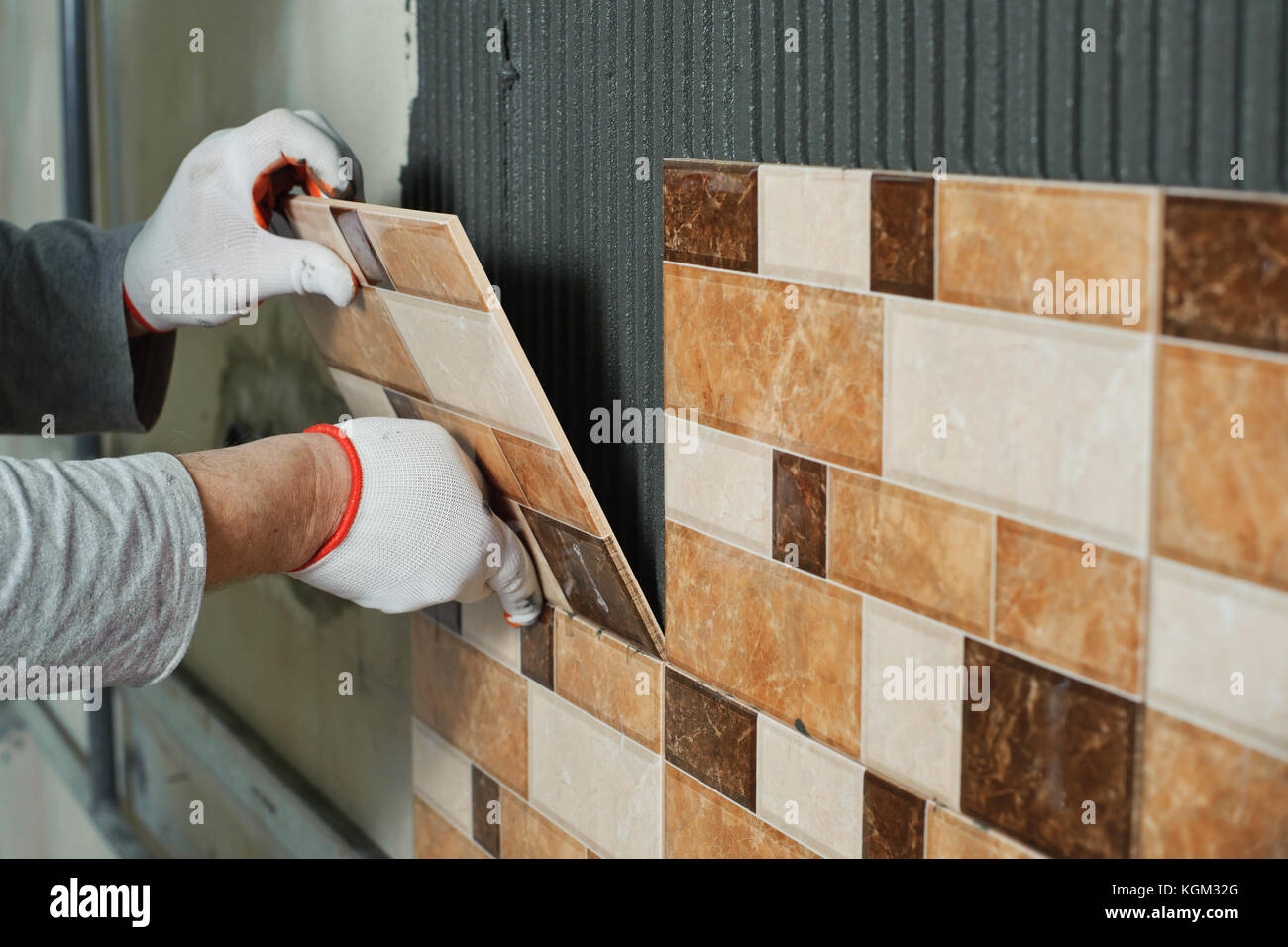 Laying Ceramic Tiles. Tiler placing ceramic wall tile in position over