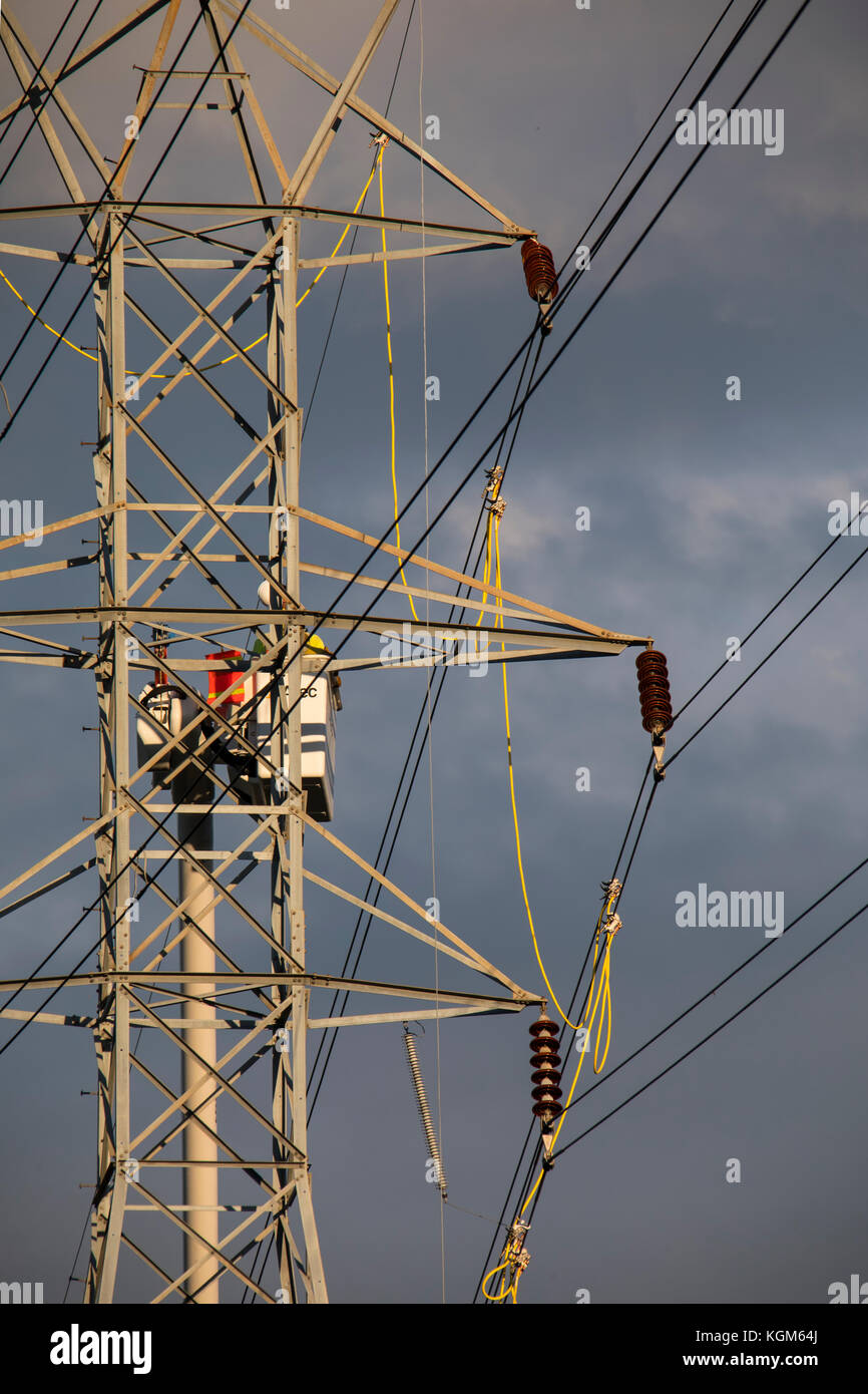 Electric company linemen work on transmission lines repairing wind
