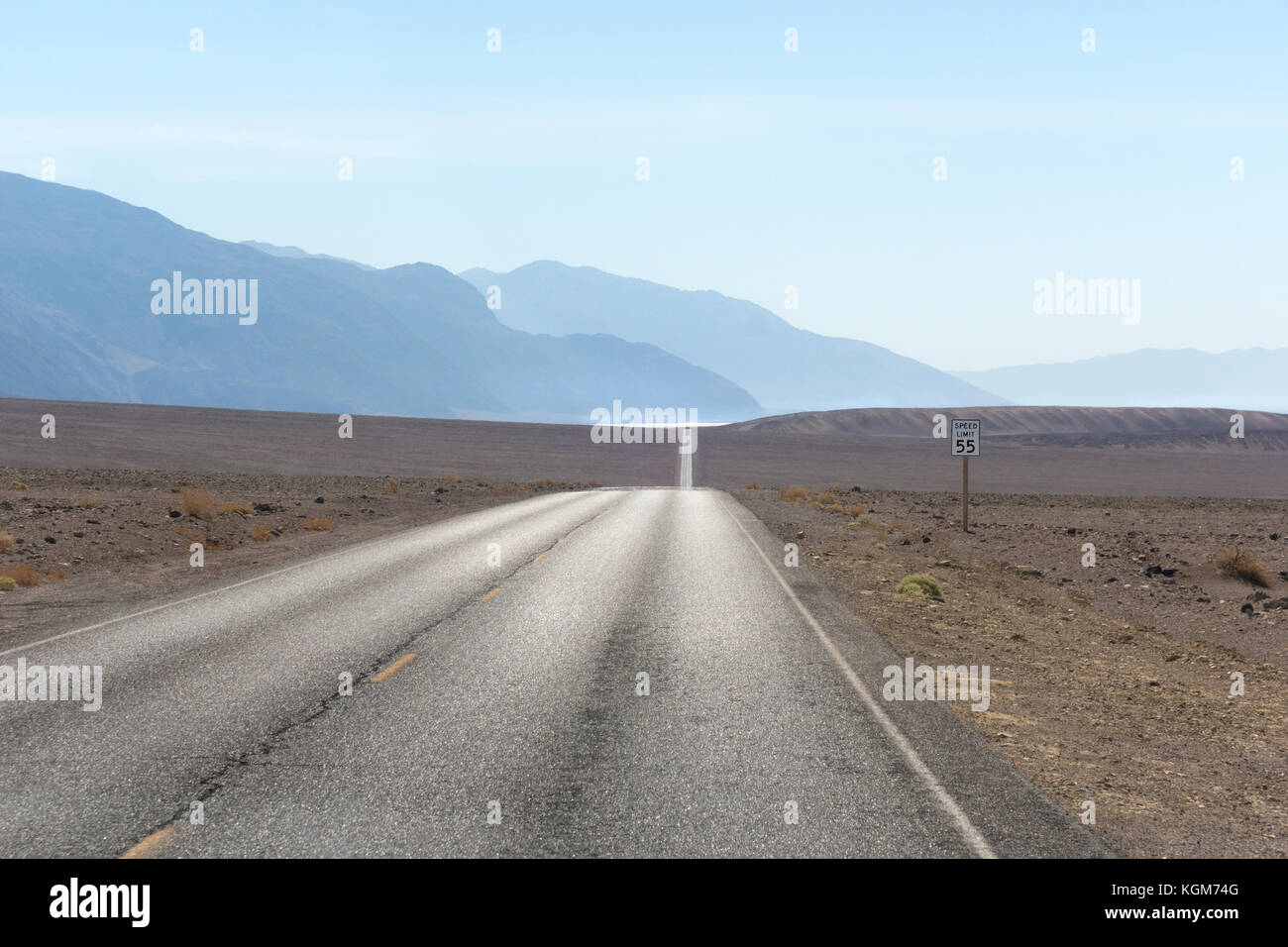 Empty desert road. Death Valley Badwater Road with Badwater Basin shimmering in the distance. Stock Photo