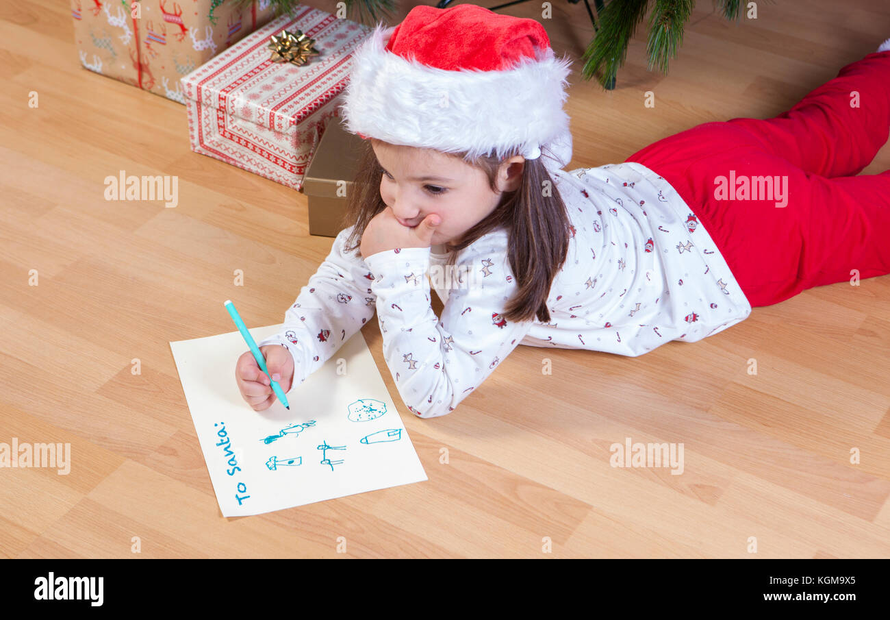 Little girl preparing The Santa Letter. She painting a sheet with header in English Stock Photo
