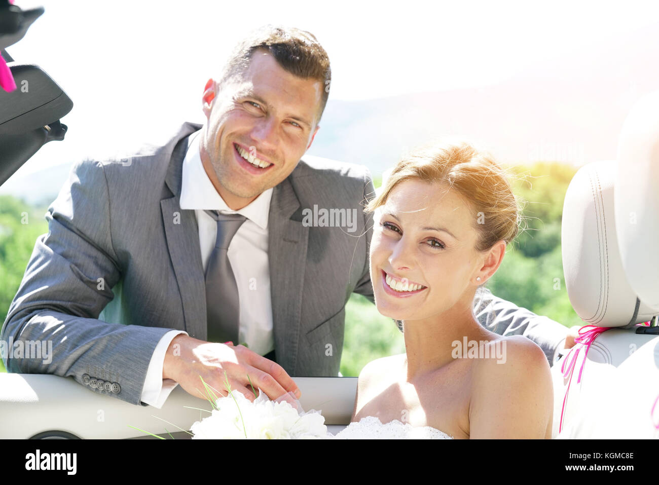 Groom leading bride to get in convertible car Stock Photo - Alamy
