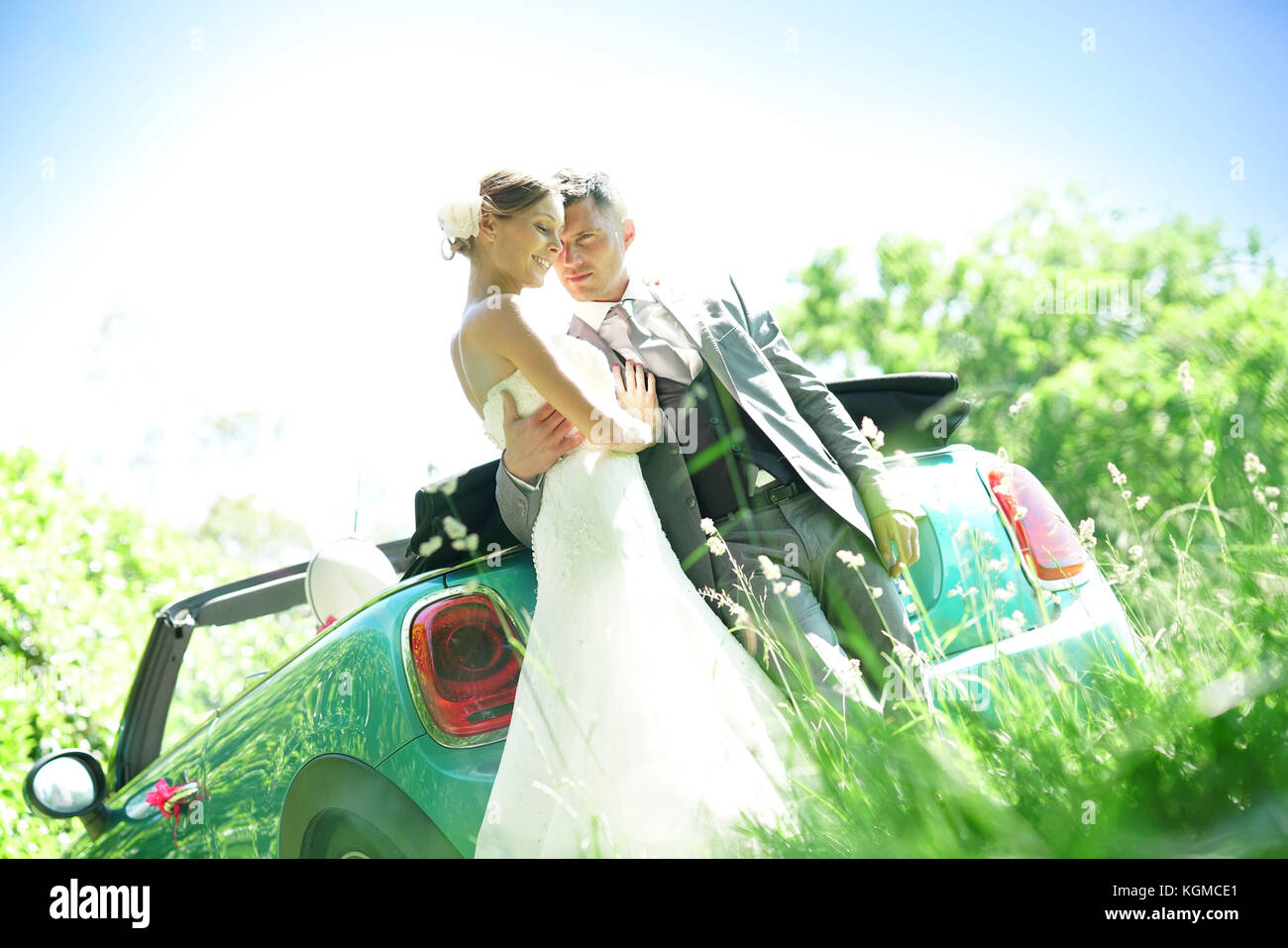 Beautiful couple on their wedding day standing by car Stock Photo - Alamy