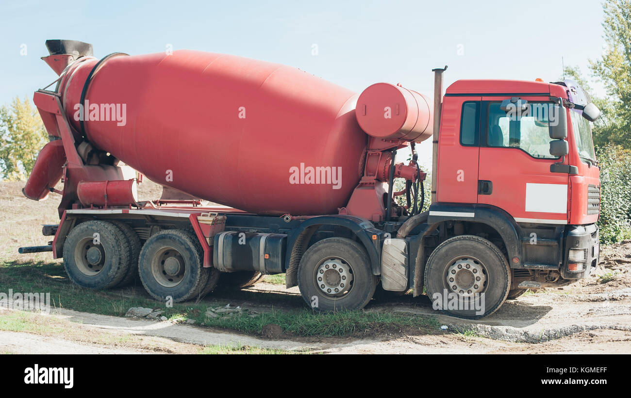 Red concrete mixer vehicle on the construction site. Construction