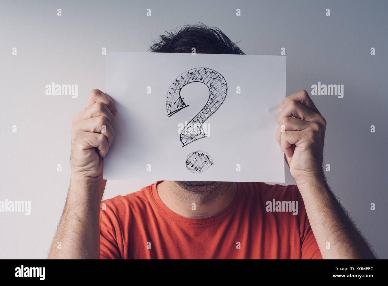 Question mark, looking for answers. Man holding paper with scribbled interrogation point, query, or eroteme punctuation Stock Photo
