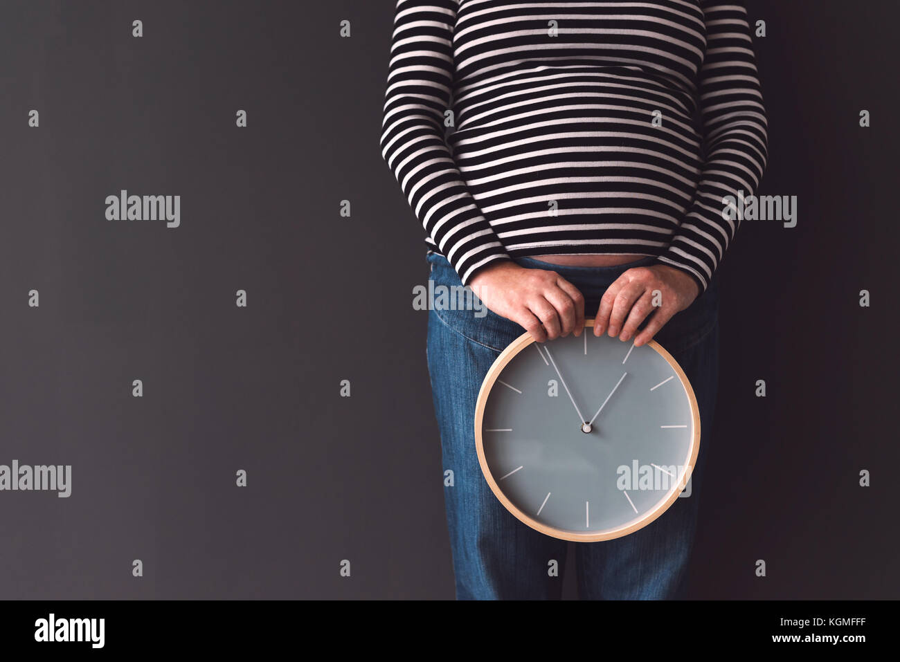 Pregnant female with vintage alarm clock expecting baby in third trimester of pregnancy Stock Photo