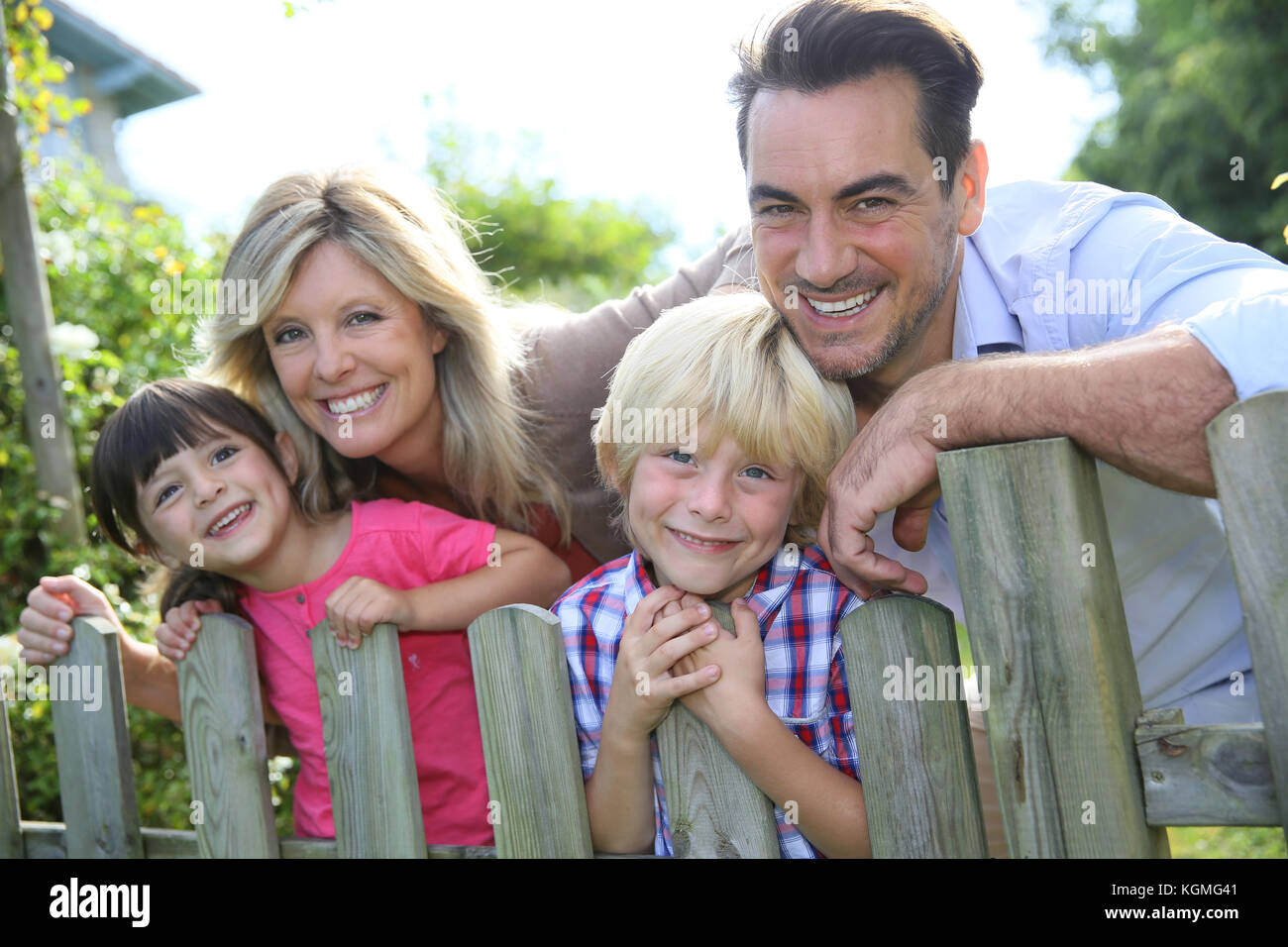 Happy family leaning on fence by country home Stock Photo Alamy