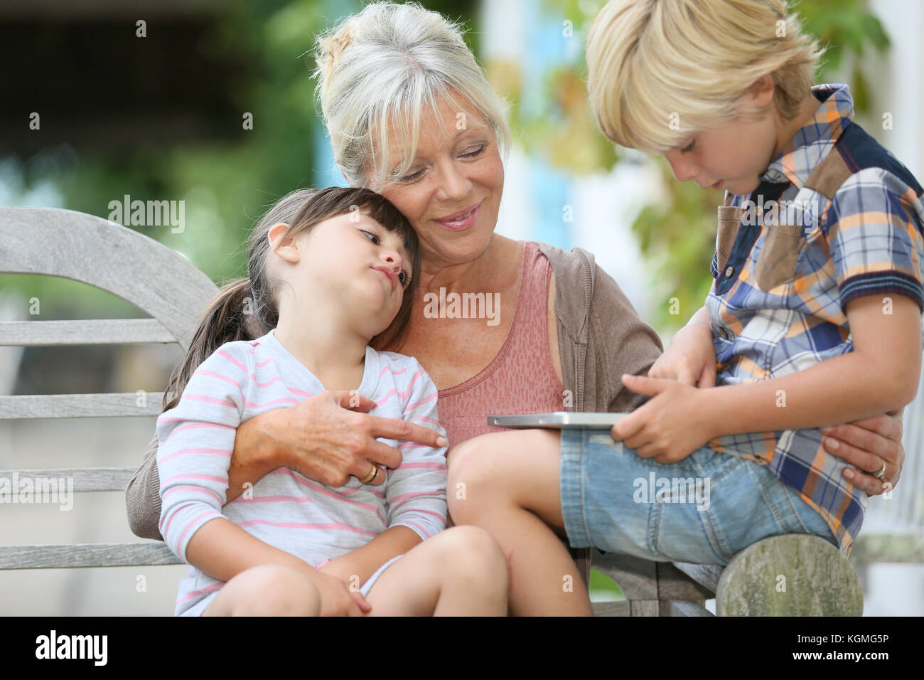 Grandmother with kids playing games on tablet Stock Photo