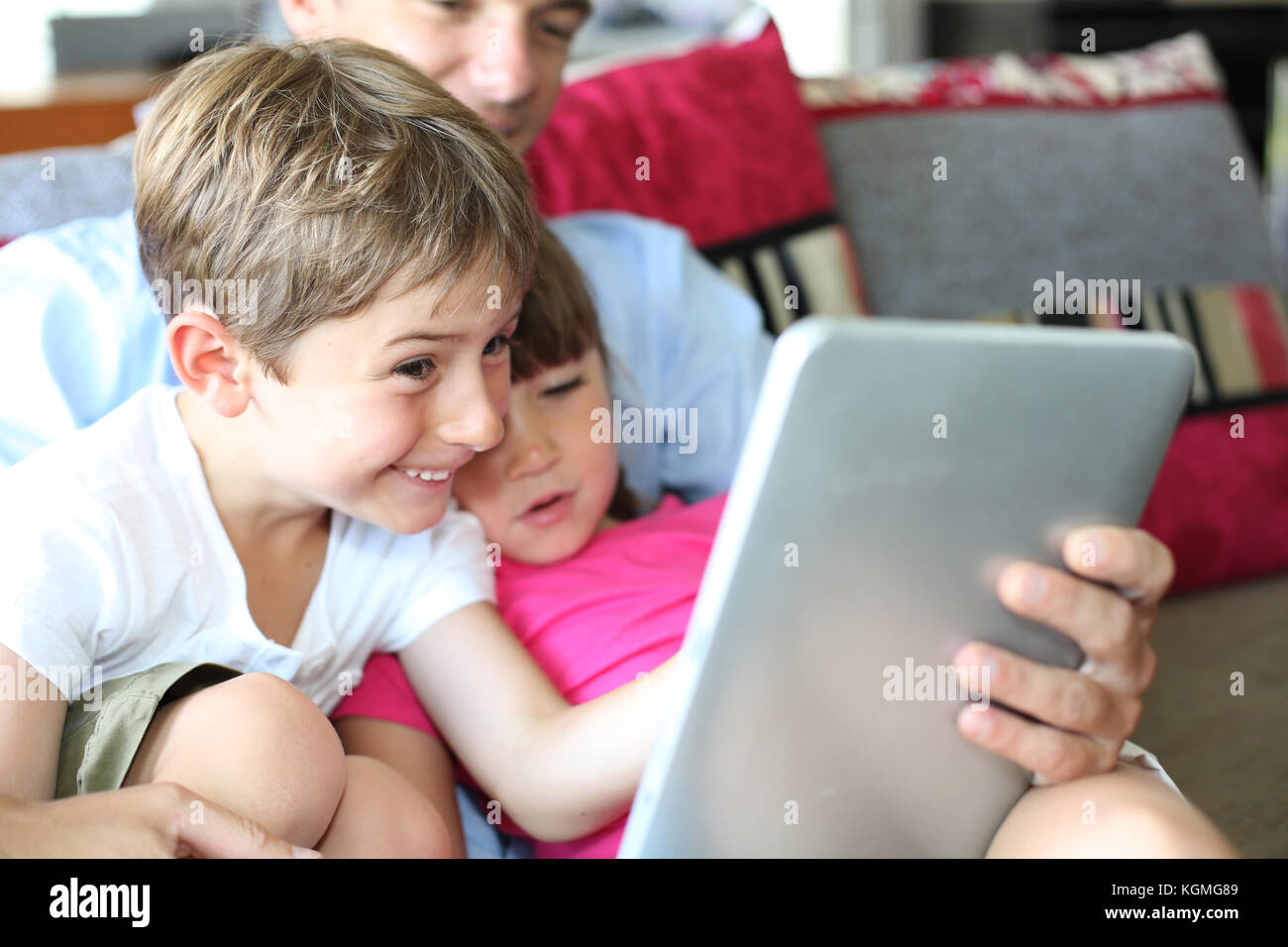 Father and children playing with tablet at home Stock Photo