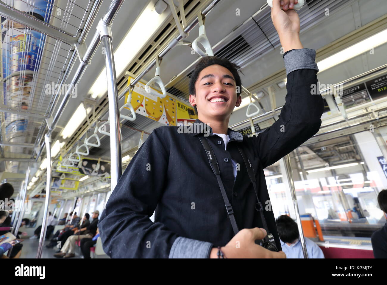 Foreigner Passenger in Japan Transport Train holding Hand Rail and Smiling. Model Release for