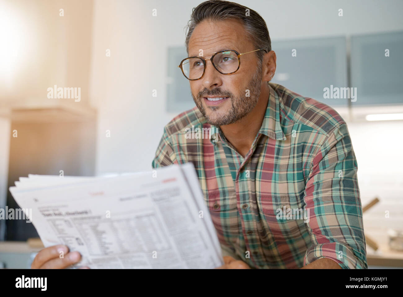 Handsome mature man at home reading newspaper Stock Photo - Alamy