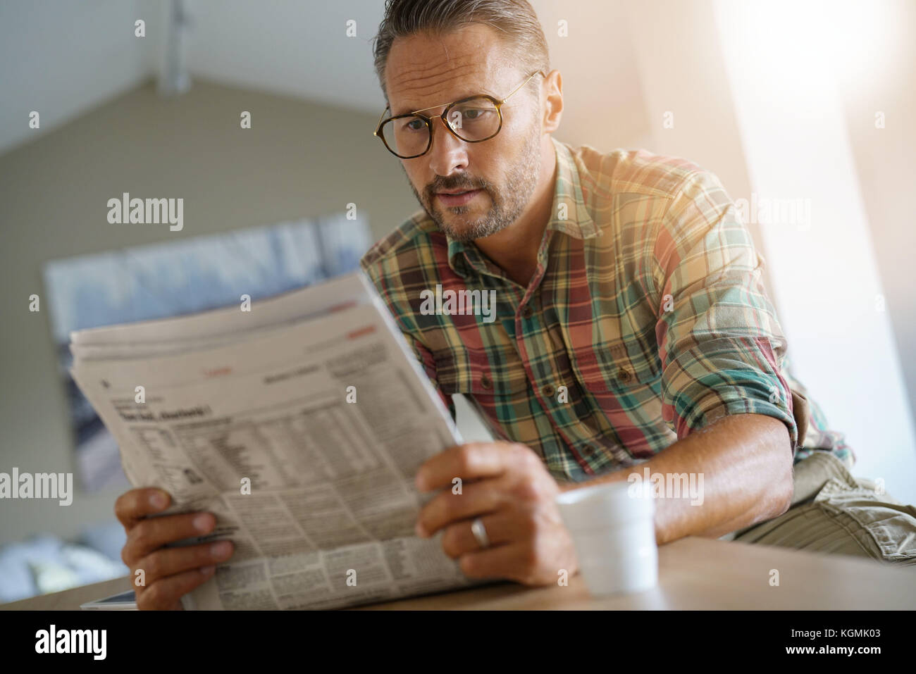 Handsome mature man at home reading newspaper Stock Photo - Alamy