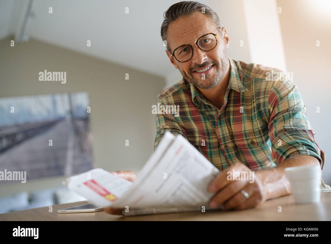 Handsome mature man at home reading newspaper Stock Photo - Alamy