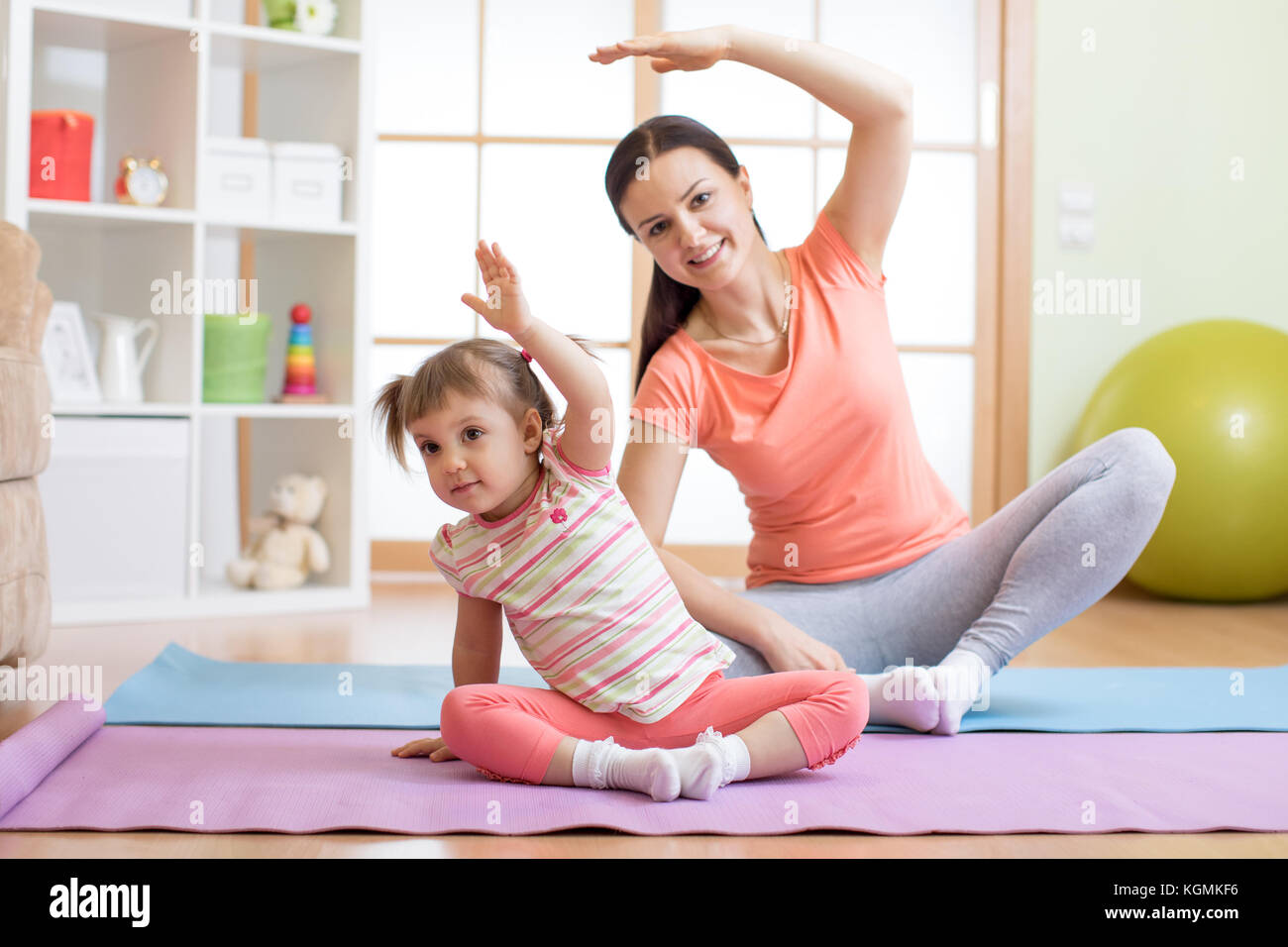 Active mother and child daughter are engaged in fitness, yoga, exercise at home Stock Photo