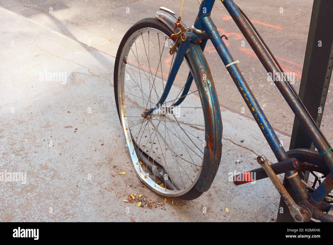 Broken front wheel with loose tyre on an abandoned rusty bicycle