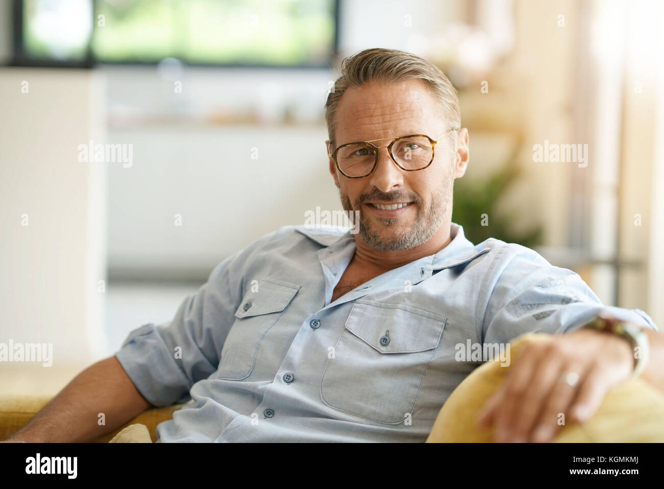 Handsome mature man with eyeglasses relaxing in sofa at home Stock ...
