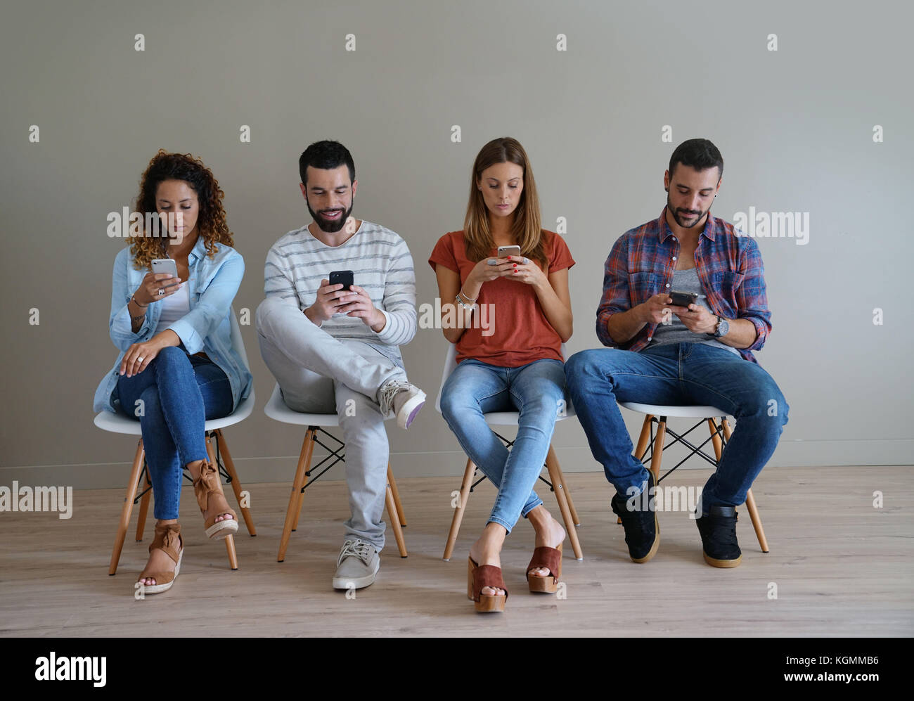 Young people in waiting room looking at smartphone Stock Photo