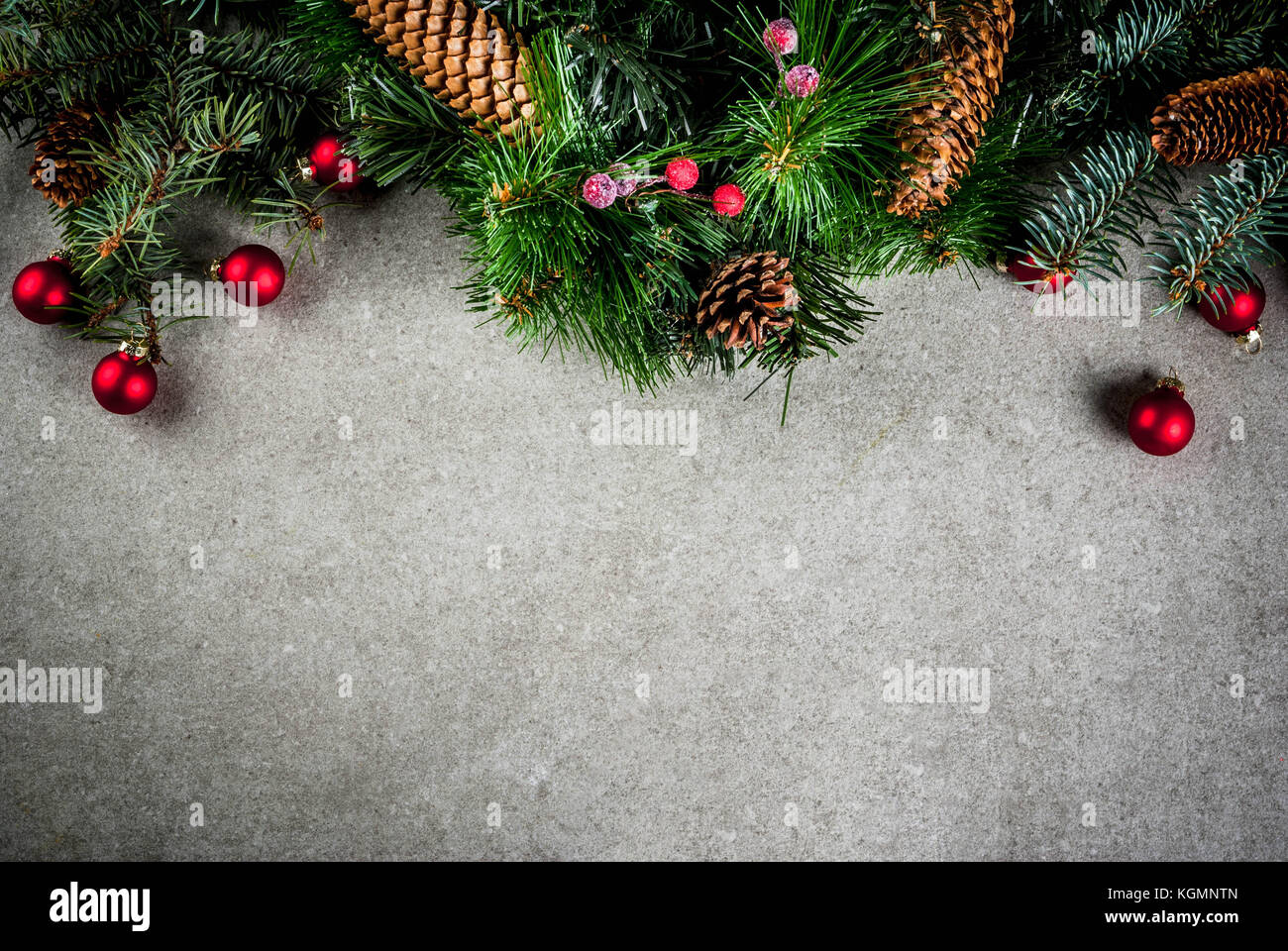 Christmas fir tree branch with pine cones and decorations on grey stone ...