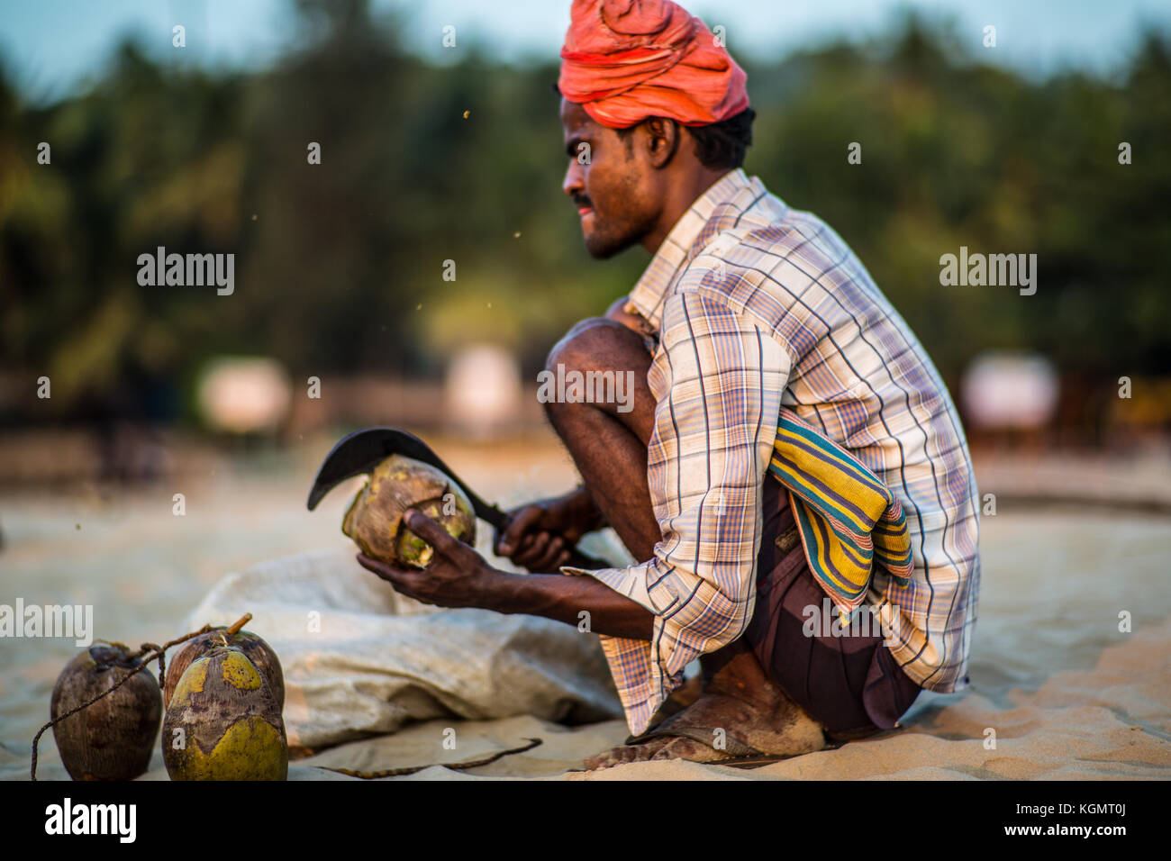 A coconut salesman opening his coconuts on the beach of Gokarna, India