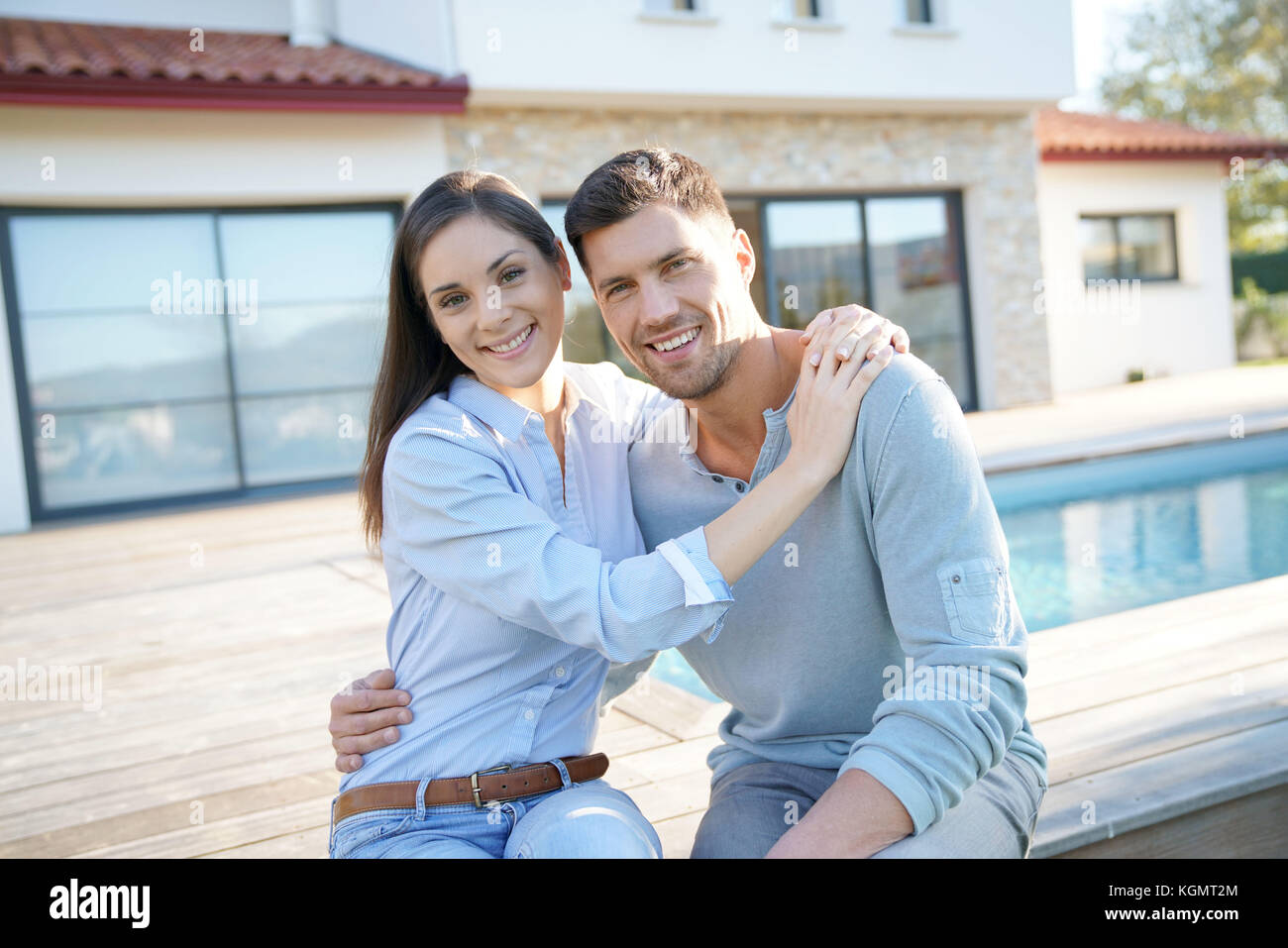 Cheerful young couple sitting in front of new home Stock Photo