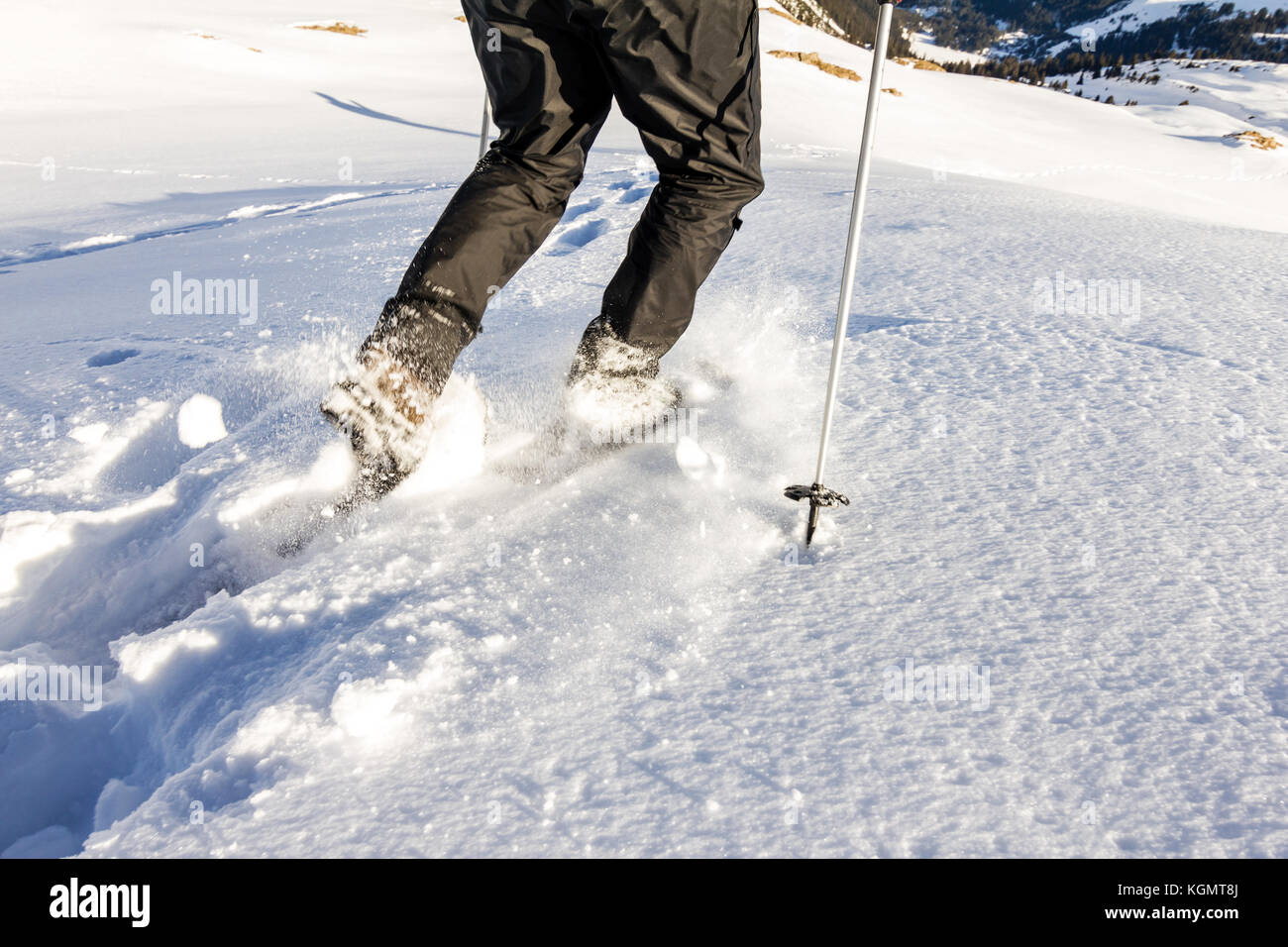 Man running downhill through deep snow with snoeshoes and hiking sticks. Stock Photo