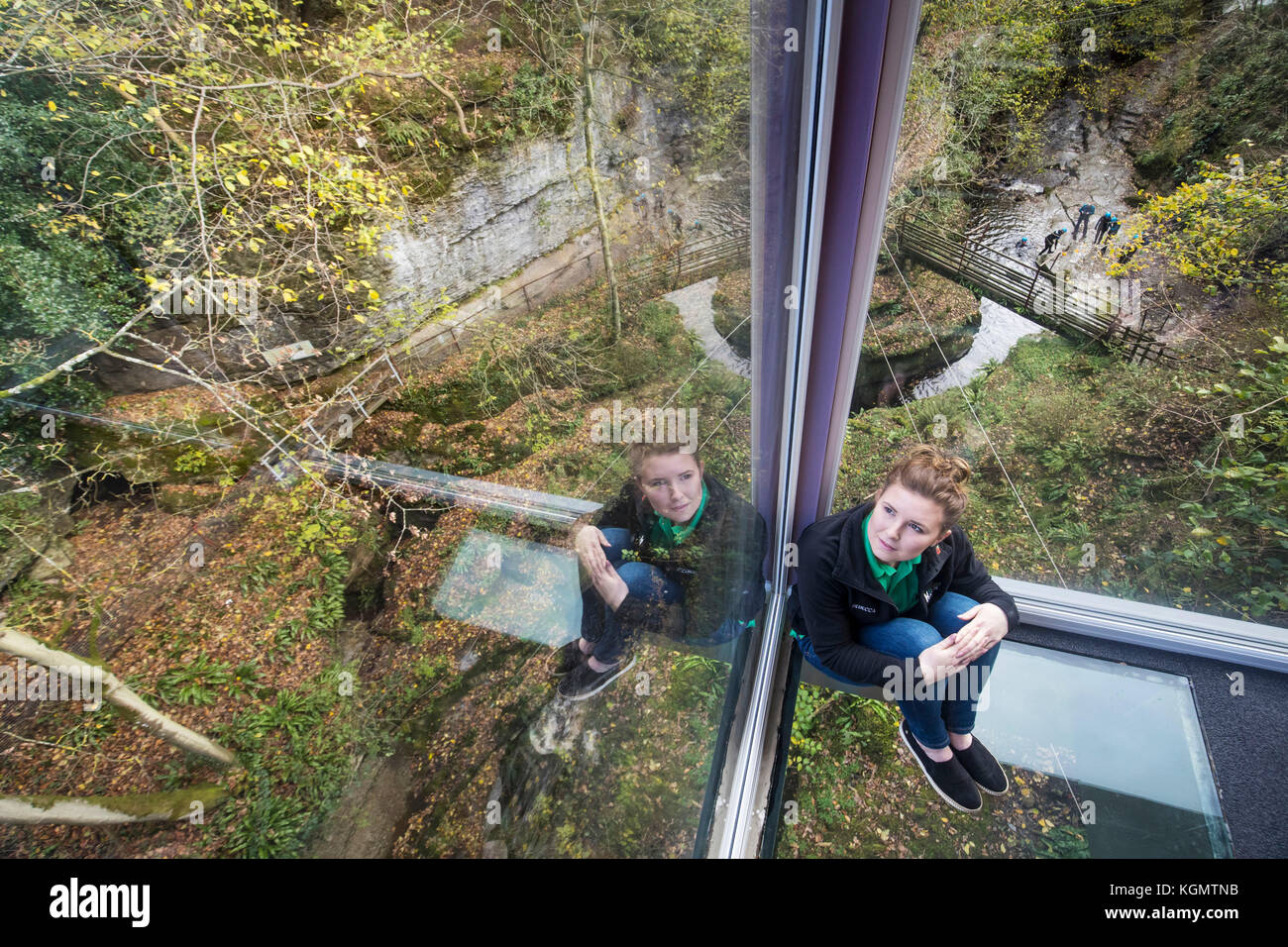 Rebecca Verity sits on the glass floor of a new cantilevered extension over one of Yorkshire's most spectacular natural sights which reaches out over How Stean Gorge, a unique limestone gorge in the Yorkshire Dales, with floor to ceiling glass walls and glass panels in the floor. Stock Photo