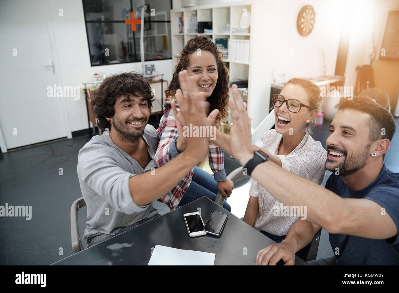 Group of working people giving one another high five Stock Photo - Alamy