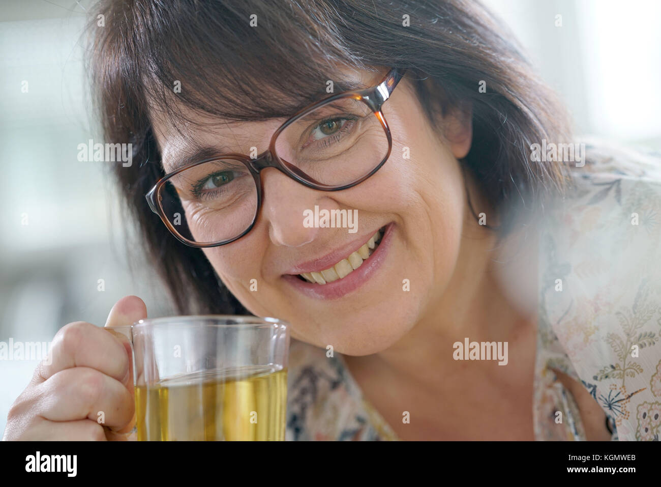 Smiling mature woman with eyeglasses drinking infusion Stock Photo Alamy