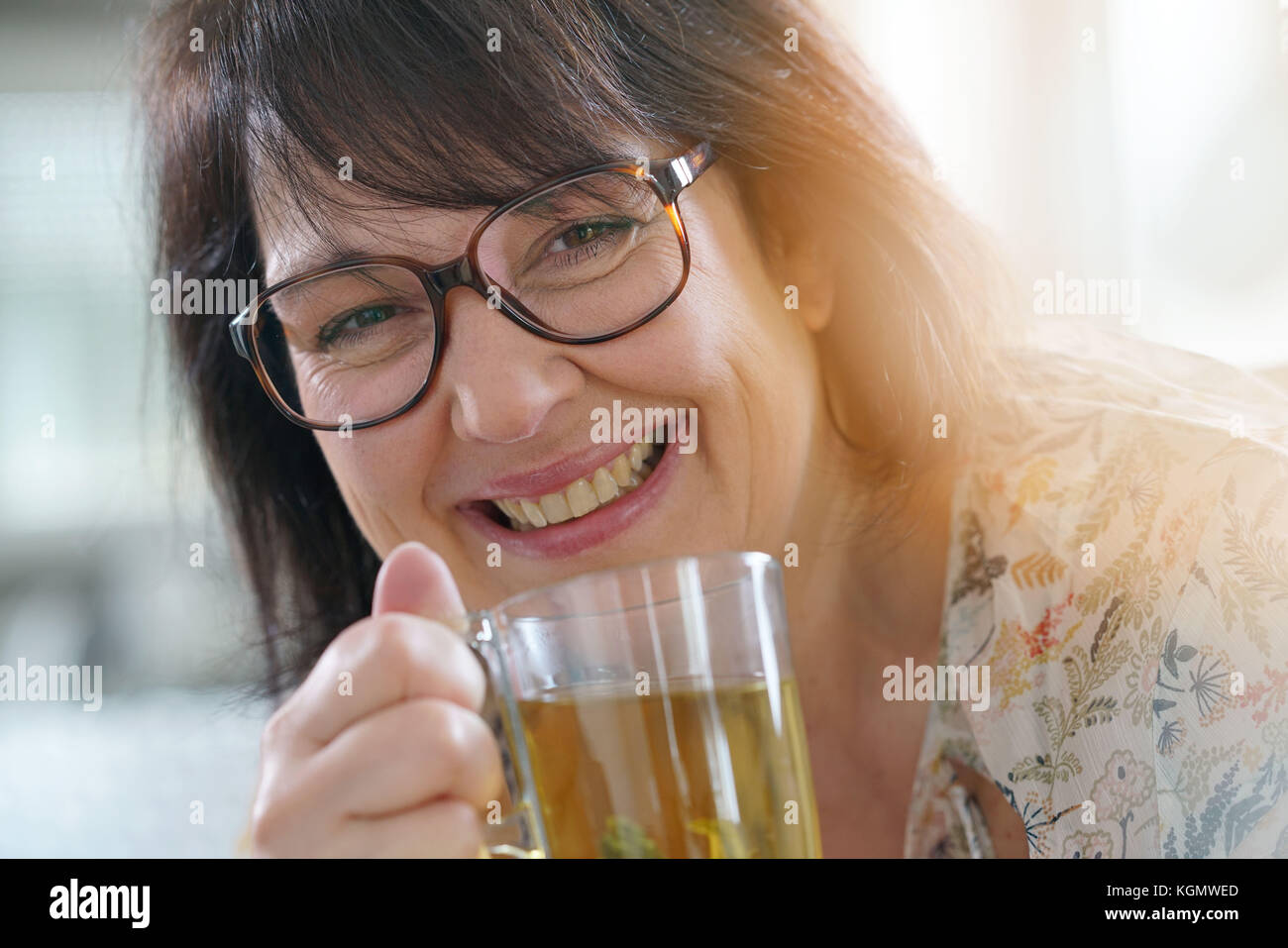 Smiling mature woman with eyeglasses drinking infusion Stock Photo Alamy