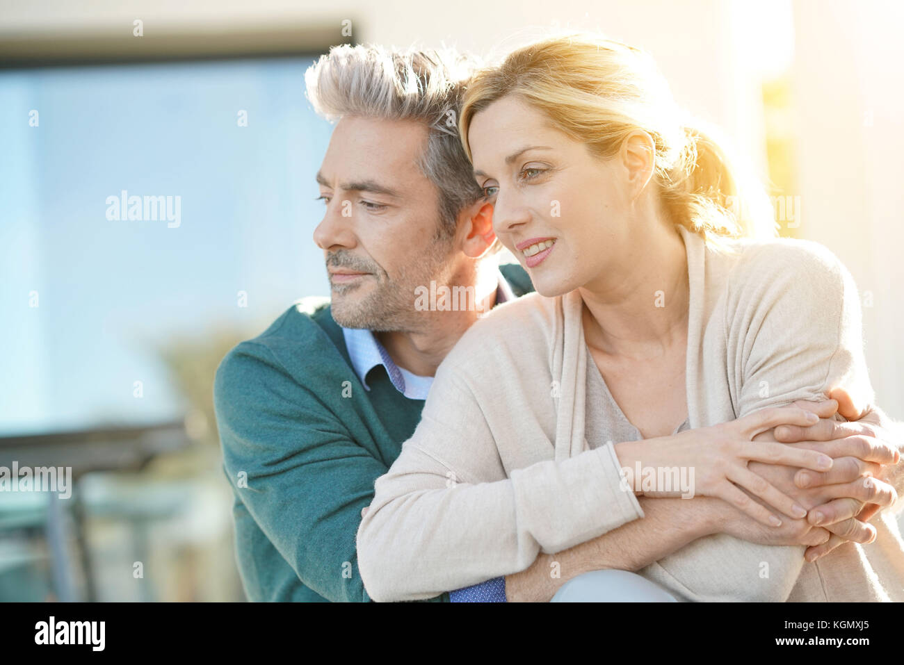 Cheerful middle-aged couple sitting in front of new home Stock Photo