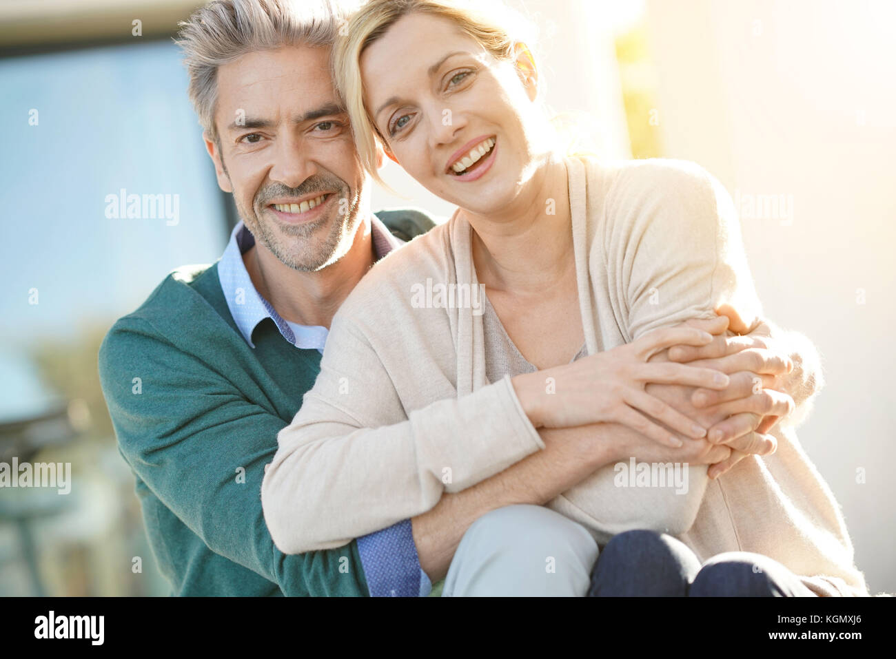 Cheerful middle-aged couple sitting in front of new home Stock Photo