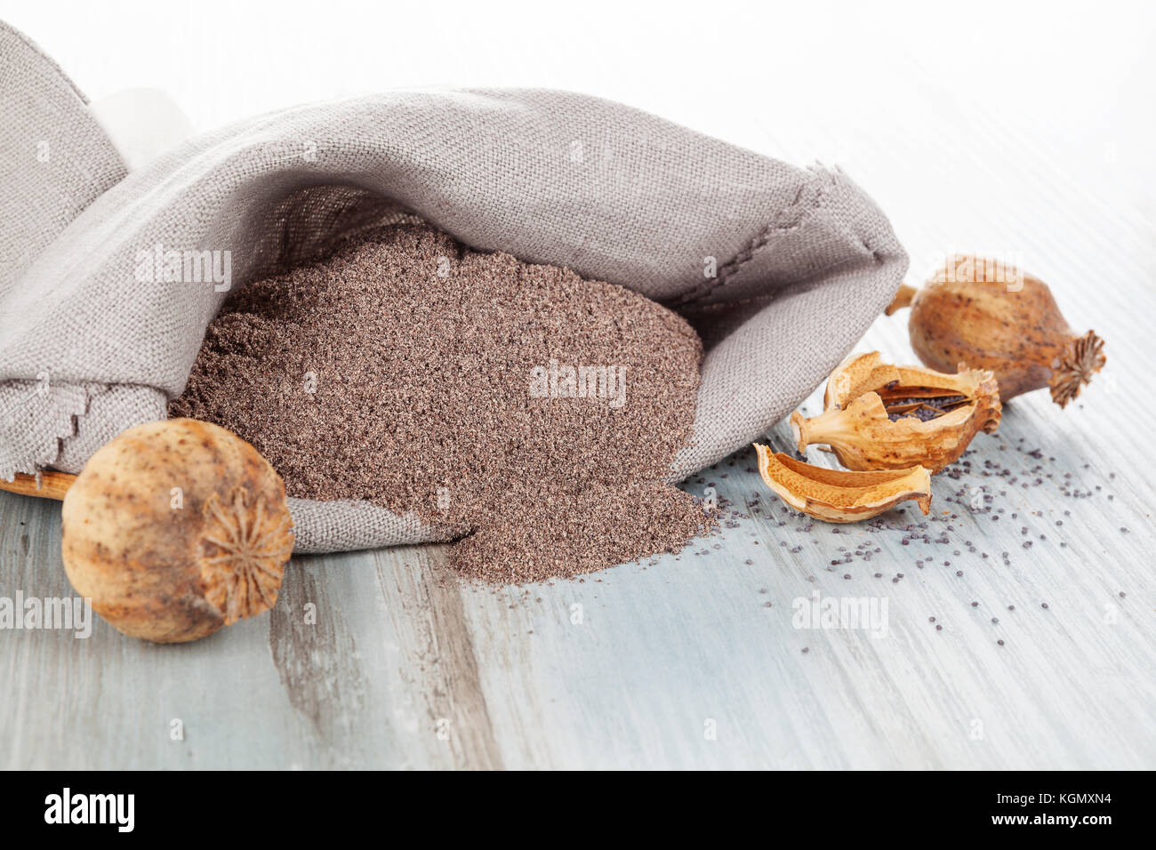 Poppy seeds with poppy flour in burlap bag on wooden table. Coeliac disease concept. Stock Photo
