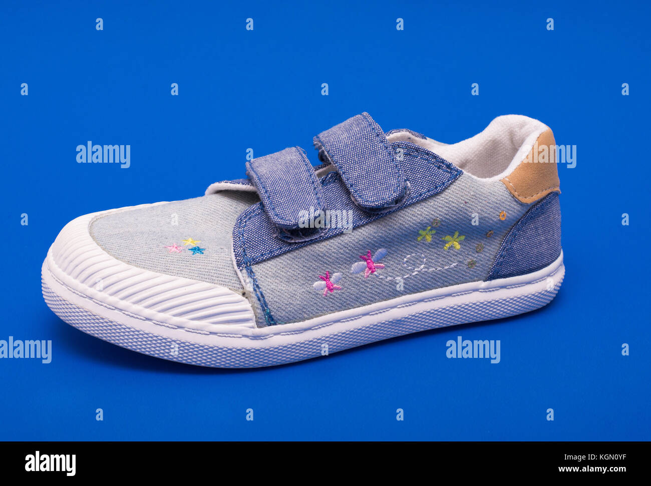 Pair of fashion denim baby shoes for the toddlers feet. Kids sneakers isolated on blue background Stock Photo
