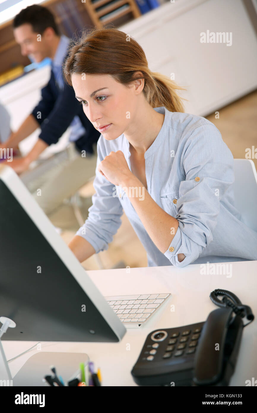 Young woman in office working on desktop Stock Photo - Alamy