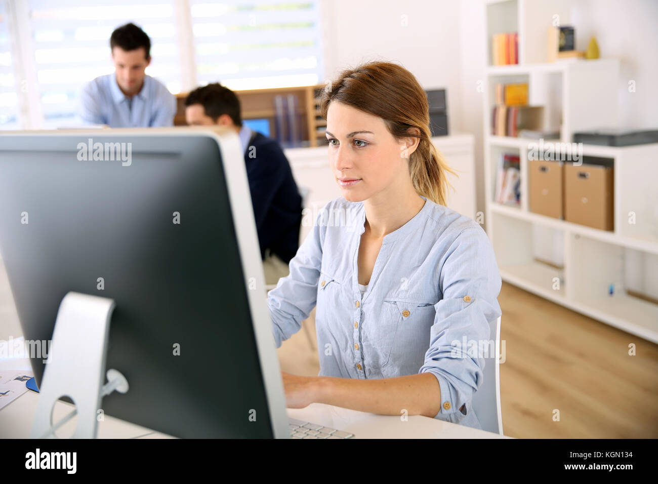 Young woman in office working on desktop Stock Photo - Alamy
