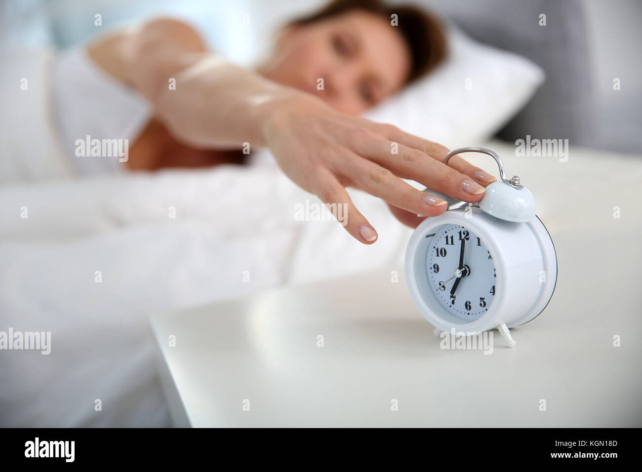 Woman turning alarm clock off in morning Stock Photo Alamy