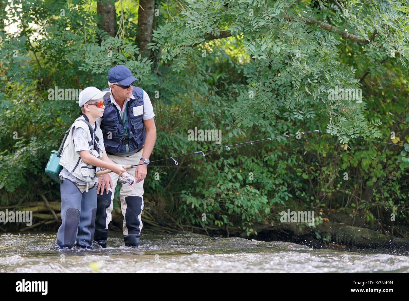 Man teaching son how to fish in river Stock Photo - Alamy