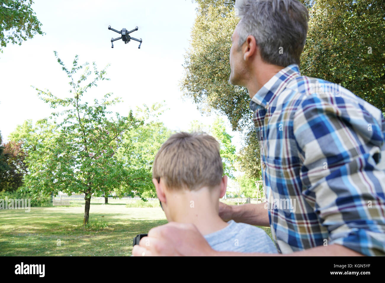 Father and son playing with flying drone in garden Stock Photo - Alamy