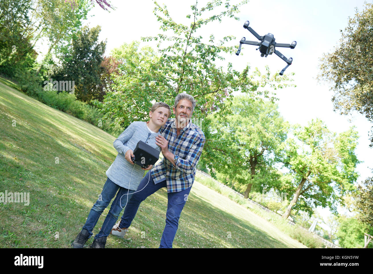 Father and son playing with flying drone in garden Stock Photo - Alamy