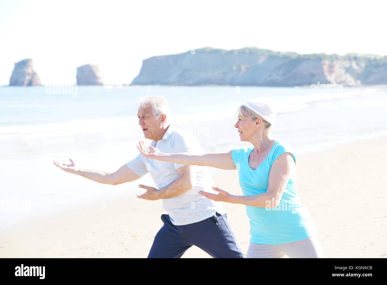 Senior couple doing stretching exercices on the beach Stock Photo - Alamy