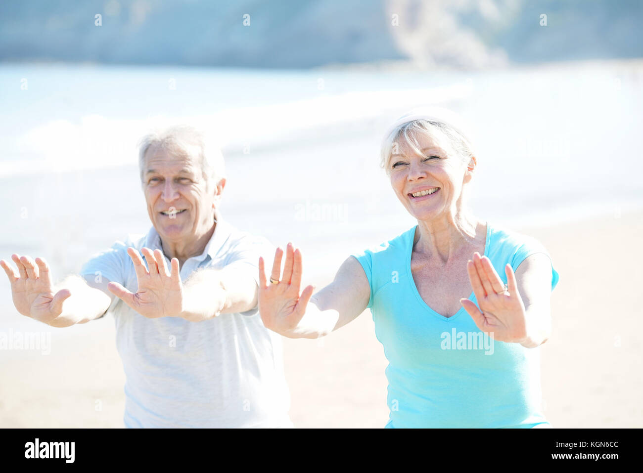 Senior couple doing stretching exercices on the beach Stock Photo - Alamy