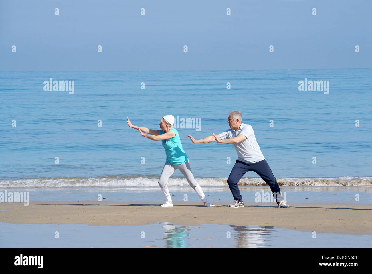 Senior couple doing stretching exercices on the beach Stock Photo - Alamy