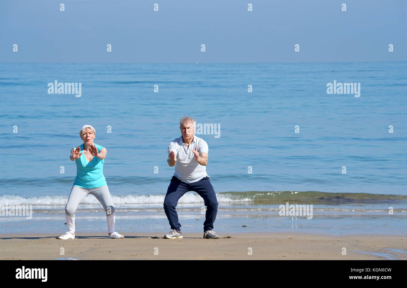 Senior couple doing stretching exercices on the beach Stock Photo - Alamy