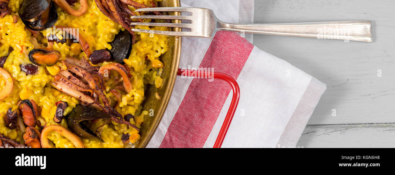 Seafood Paella in Traditional Pan on Rustic Wooden Table Stock Photo