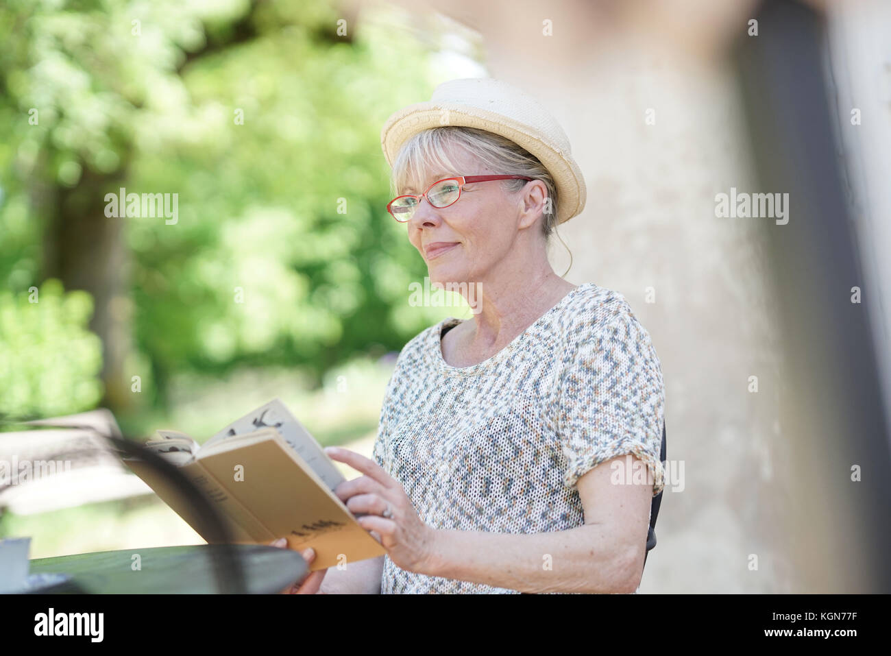 Senior woman relaxing in garden and reading book Stock Photo - Alamy