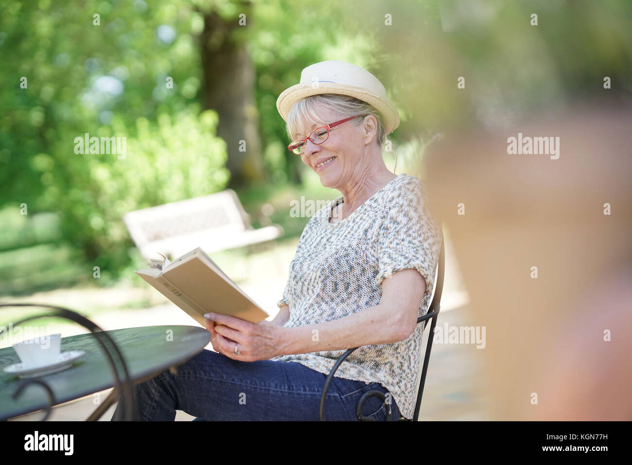 Senior woman relaxing in garden and reading book Stock Photo - Alamy