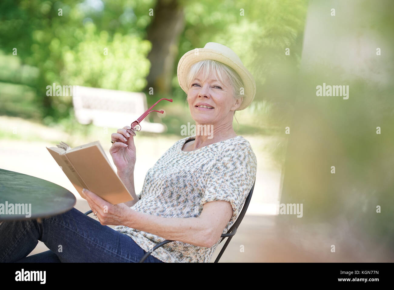 Senior woman relaxing in garden and reading book Stock Photo - Alamy