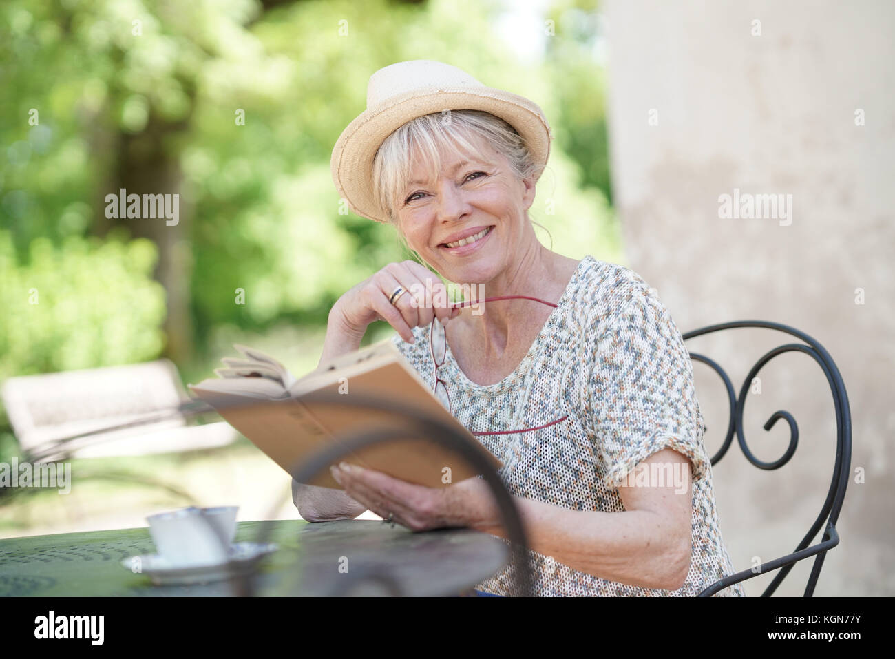 Senior woman relaxing in garden and reading book Stock Photo - Alamy