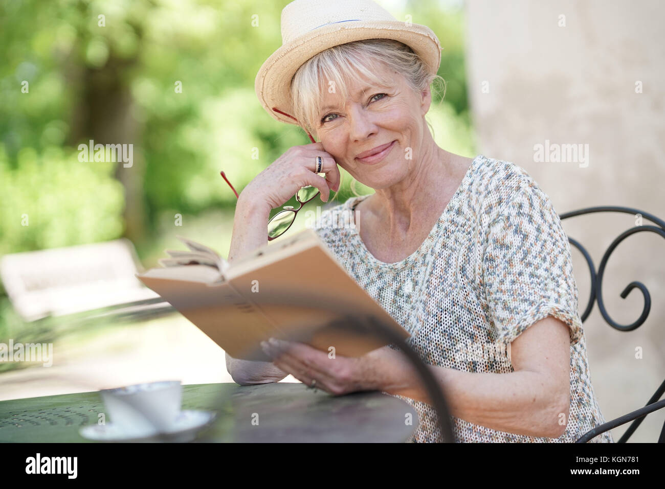 Senior woman relaxing in garden and reading book Stock Photo - Alamy