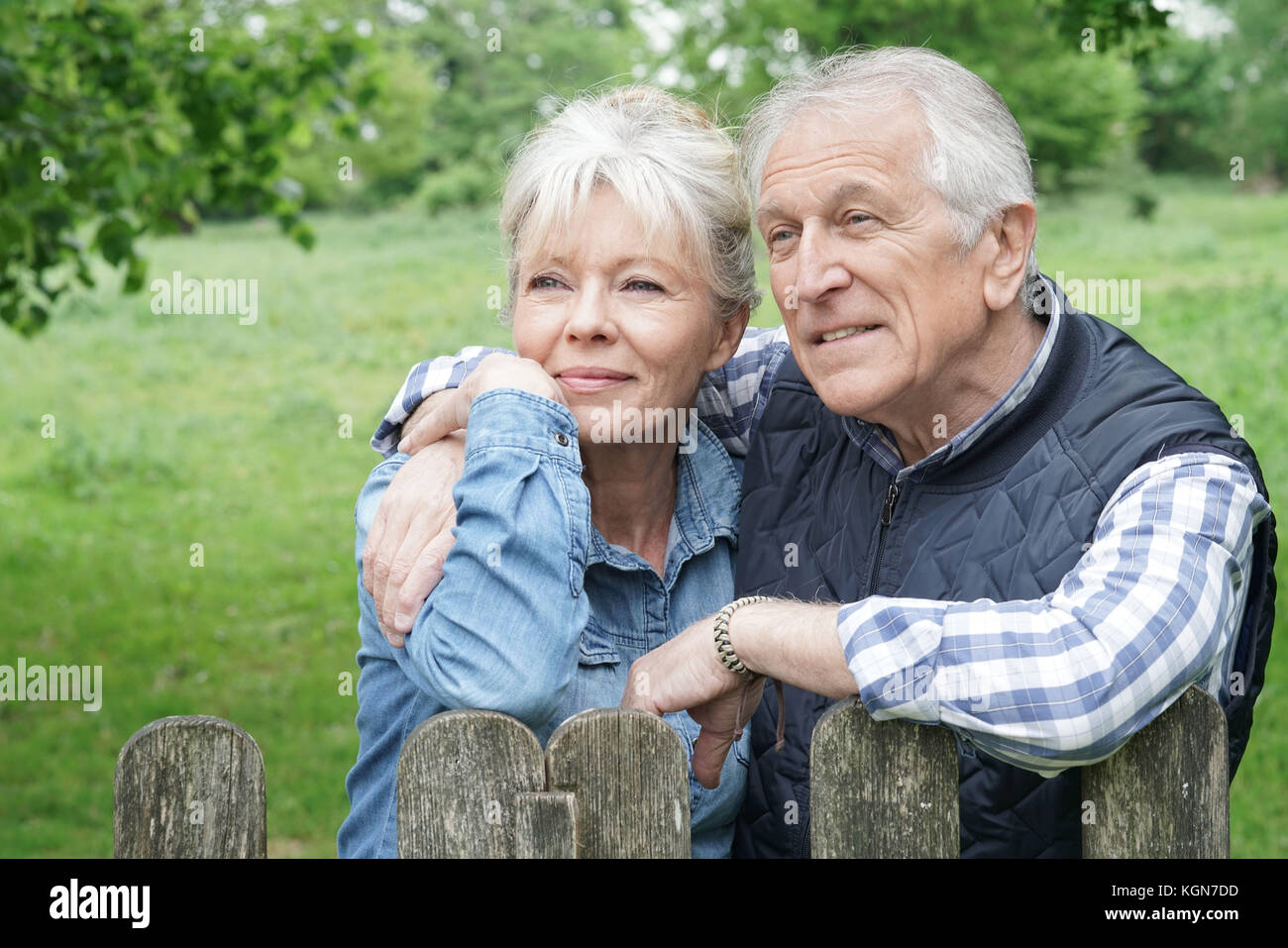 Portrait of senior couple leaning on fence in countryside Stock Photo