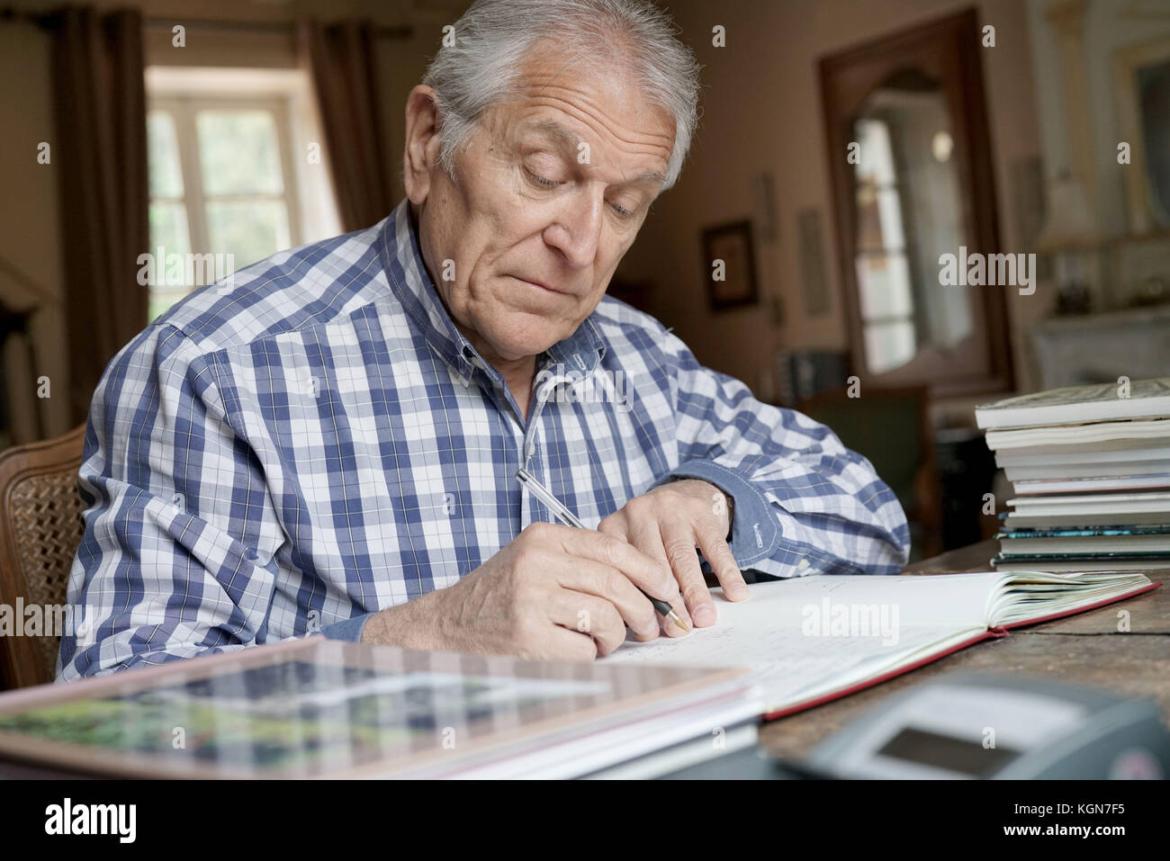 Senior man at home relaxing and writing on notebook Stock Photo